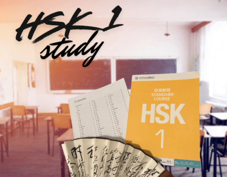 a picture of the orange and white HSK 1 study booklet in a classroom setting, accompanied by a delicate Chinese fan with beautiful calligraphy written on it.